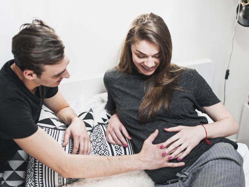 man-touching-pregnant-woman-s-belly-bedroom